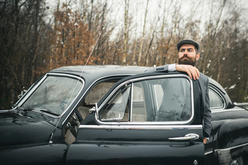 Escort man or security guard. Bearded man in car. Call boy in vintage auto. Retro collection car and auto repair by mechanic driver. Travel and business trip or hitch hiking