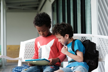 African and Caucasian using tablet at kindergarten school, kid education, online study, technology lifestyle