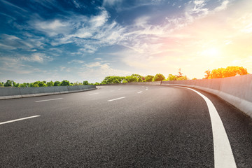 Fototapeta premium Empty asphalt road and woods landscape at sunset