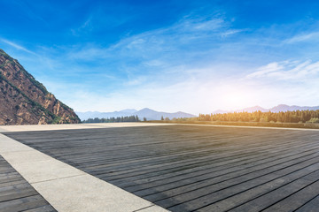 Wooden board square floor and hills with sky clouds