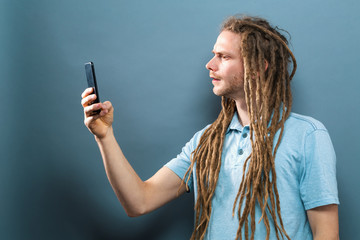 Young man staring at his cellphone on a gray background