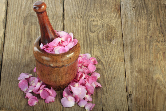 petals of rose in martar on wooden background