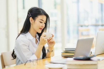 Businesswoman working on laptop while drinking coffee in the office	