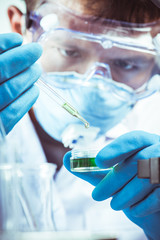 Conical flask in scientist hand with microscope and lab glassware background, Laboratory research...