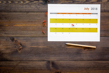 Planning. Point the date in calendar by pushpin. Set the goal. Choose date. Calendar on dark wooden background top view copy space