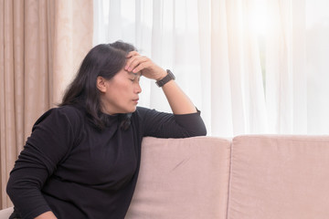 woman suffering headache sitting on a sofa