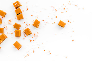 Trendy dessert. Salted caramel. Caramel cubes sprinkled by salt crystals on white background top...