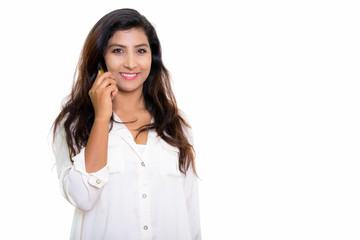 Studio shot of young happy Persian woman smiling while talking o
