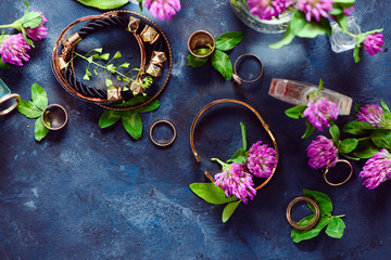 Golden bracelets and rings in a feminine style concept with clover flowers on a dark background. Beautiful summer accessories.