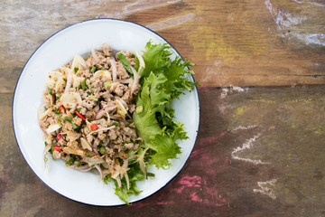 Top view of Thai food spicy minced pork salad on wood background