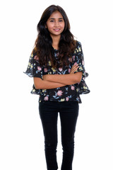 Studio shot of young happy Persian woman smiling and standing wi