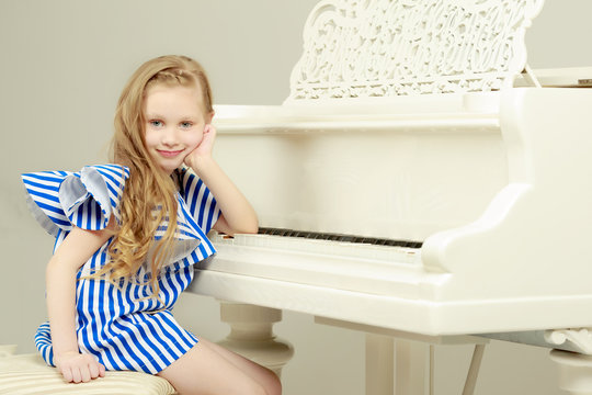 Adorable little blond girl in very short summer striped dress.