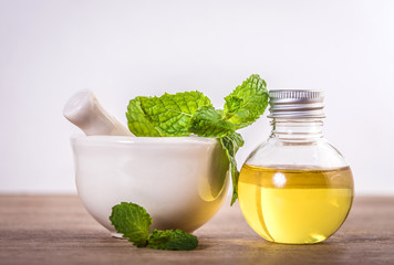 Aroma essential oil from a peppermint in the bottle on the table with fresh green mint leaf