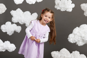 girl playing with clouds, shooting in the studio on a gray background, happy childhood concept