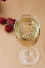 Glass of sparkling wine with cherry, summer drink, pink peony flowers on table