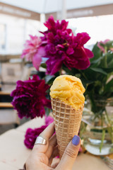 Female hand holding waffle cone with ice cream