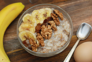 Top view of a Granola Bowl, Muesli with Oats, Nuts and Dried Fruit on Wooden table. Bannana, nuts, fruits. Healthy Breakfast. Diet.