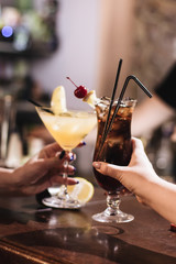 Delicious cocktail with ice cubes, cherry and straws in bar