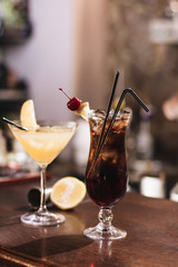 Delicious cocktail with ice cubes, cherry and straws in bar