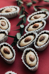 Flat lay of delicious praline sweets with almonds on red background