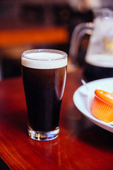 Stout (Black Beer) in glass on wooden table in the bar.