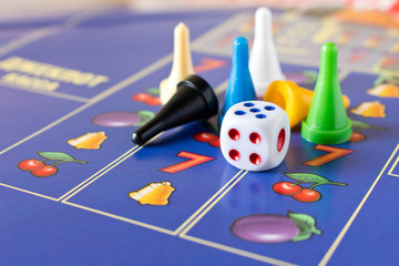 Multi-colored game chips with dice on the playing board. Board game
