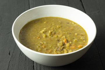 Rustic beef, vegetable and barley soup on black table