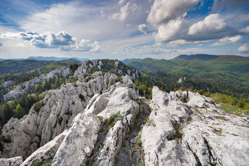 Hiking through the rugged karst landscape of eroded limestone peaks surrounded by forest, in Bijele...