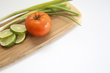 Wooden board with delicious tomato, lime, and chive