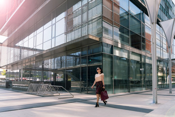 Young elegant woman walking in front of office building