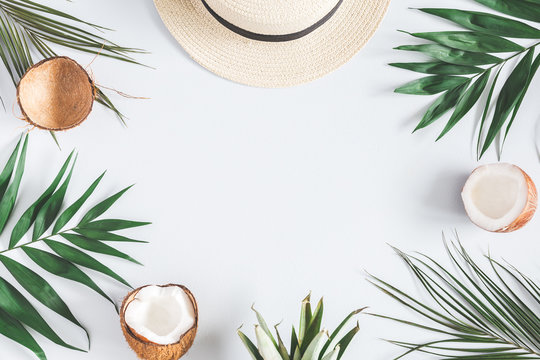 Summer composition. Tropical palm leaves, hat, coconut on pastel blue background. Summer concept. Flat lay, top view, copy space