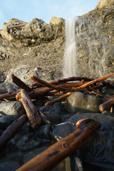 waterfall over cliff onto drift wood