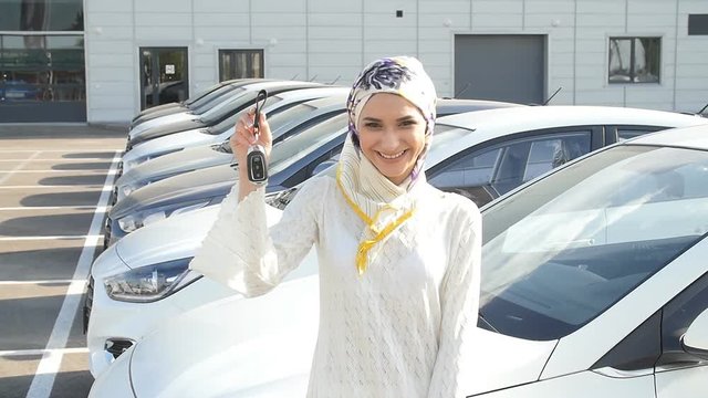Muslim woman in hijab with car key outdoors