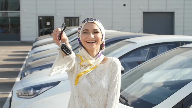 Muslim woman in hijab with car key outdoors