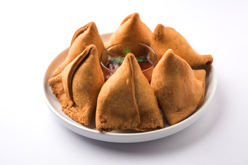 Samosa snack served with tomato ketchup and mint chutney