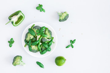 Green vegetable salad on pastel blue background. Vegan, vegetarian concept. Flat lay, top view, copy space