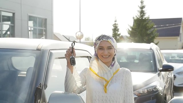 Muslim woman in hijab with car key outdoors