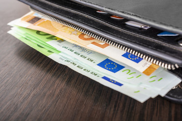 Open wallet with euro cash 10 20 50 100 on a wooden background. Men's wallet with cash euro.