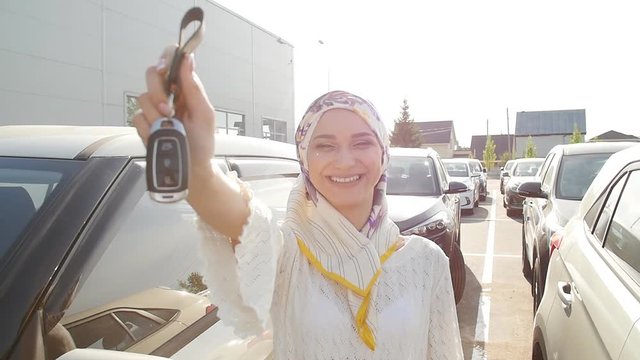 Muslim woman in hijab with car key outdoors