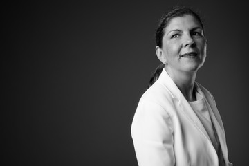 Obraz premium Mature beautiful businesswoman against gray background in black 