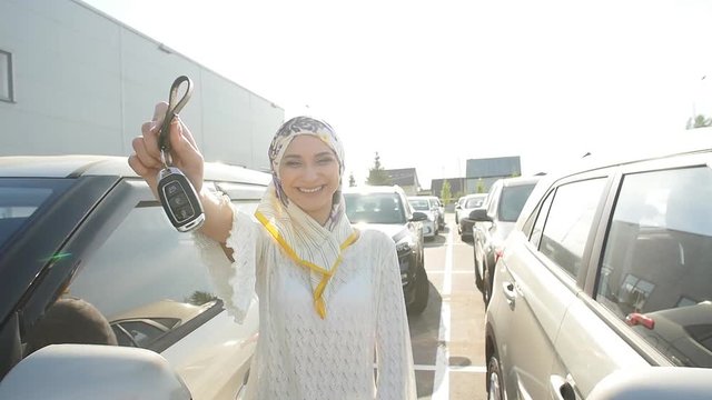 Muslim woman in hijab with car key outdoors