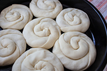 Raw twisted dough with stuffing rises in the roaster. Traditional moldavian food called platzinda