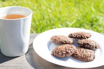 A cup of tea and the biscuits on the wooden table in the early morning. Light breakfast