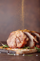 Oven-baked pork with rosemary and spices on a wooden table.