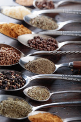 Different spices in  spoons on a wooden background.