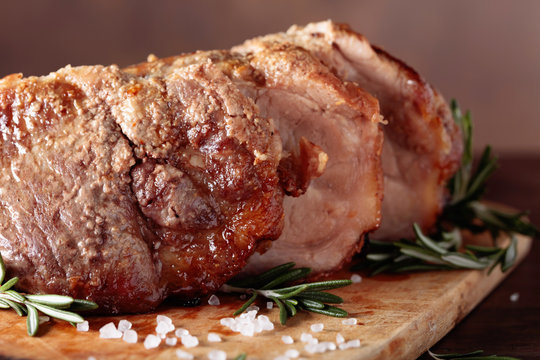 Oven-baked pork with rosemary and spices on a wooden table.