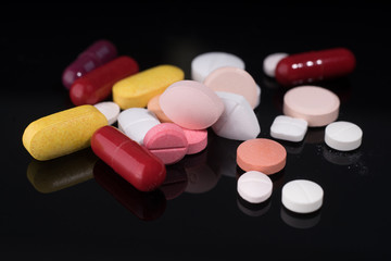 Medical pills and supplement capsule on black glass table with reflection.Studio shot.