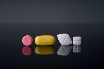 Medical pills and supplement capsule on black glass table with reflection.Studio shot.