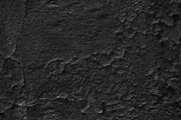 Fototapeta na wymiar Gloomy background of old black wall with weathered cracked paint