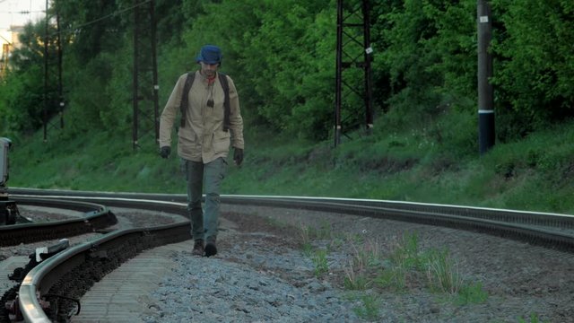 Alone ranger traveler goes along the railway tracks with hat and gun at apocalyptic world